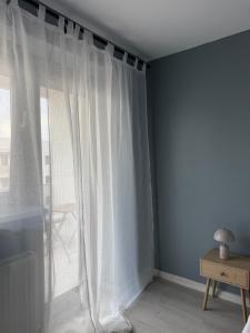 a white curtain in a room with a window at Blue Oasis Apartment - Hils Brauner in Bucharest +20 photos