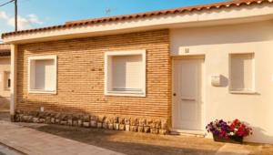 a brick house with a white door and flowers at Casa Damián in Ribaforada