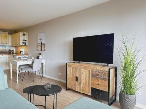 a living room with a flat screen tv on a wooden cabinet at Villa Anna I - Wohnung Strandjunge in Sankt Peter-Ording