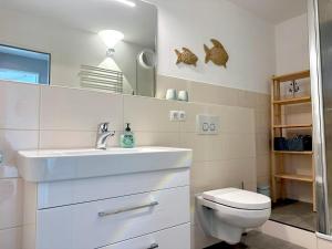 a white bathroom with a sink and a toilet at Villa Anna I - Wohnung Strandjunge in Sankt Peter-Ording +13 photos