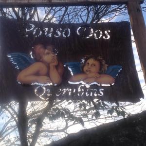 2 hommes nus portant des oreillers sur un panneau dans l'établissement Pouso dos Querubins, à Tiradentes