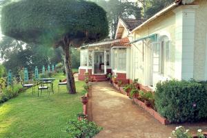 a small house with a table and a tree at Wyoming Heritage in Ooty +41 photos
