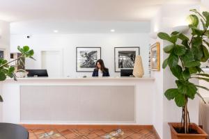 a woman sitting at a reception desk in a room with plants at Regina Cristina in Capri
