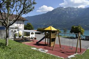 a playground with a swing set with a mountain in the background at FLORA BAY Spacious Lake and Mountain View Apartment in Niederried