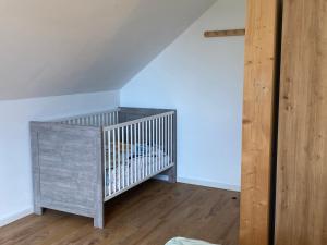 a crib in a room with a wooden floor at Schwedenhaus Fridhem mit Panoramablick auf dem Hügel in Monschau