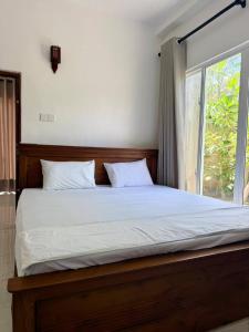 a bedroom with a large bed with a window at Blue Wave Holiday Villa in Weligama