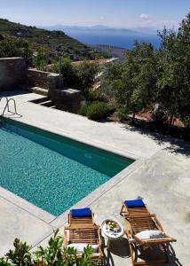 a swimming pool with two lounge chairs and the ocean at Kea Village Suites & Villas in Ioulis