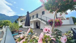 a villa with a balcony with a umbrella and flowers at Bike Apartments Curti - Waldgrün in Laives