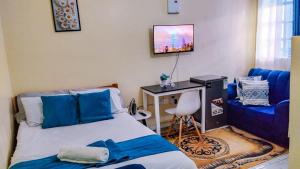 a bedroom with a bed and a tv on the wall at Des Homes in Nairobi
