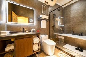 a bathroom with a toilet and a sink and a tub at Elsewhere Hotel Inn Ancient City Center Branch in Pingyao