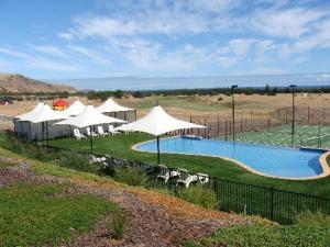 a swimming pool with white umbrellas and chairs next to at Lady Bay Hotel in Normanville