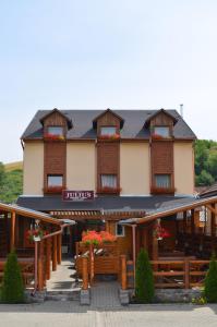 un bâtiment avec des bancs en bois devant lui dans l'établissement Juliu's Panzio Csikszereda, à Miercurea-Ciuc