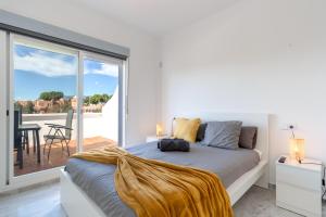 a white bedroom with a bed and a balcony at Unique Villa Scandinavia Marbella in Marbella