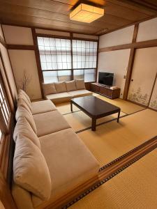 a living room with a large couch and a table at Kuro House Myoko in Myoko +57 photos