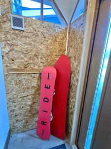 a red snowboard leaned up against a wall at Kuro House Myoko in Myoko