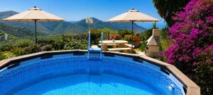 a swimming pool with a table and umbrellas at Finca Mariposa Mariposaholidays in Nerja