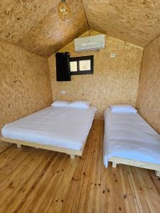 two beds in a small room with wooden floors at מאי טאי ויליג' - 8 בקתות מהממות מול הנוף in Mas'ada