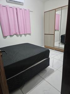 a bedroom with a bed and pink curtains at Recanto JF in Pirapora