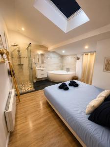 a bedroom with a large bed and a bath tub at Les Cœurs de Ribérac - Hyper centre - Climatisation - Wi-Fi in Ribérac