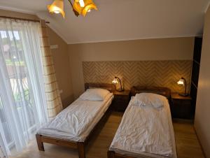 two beds in a room with two windows at Willa Arkadia in Władysławowo