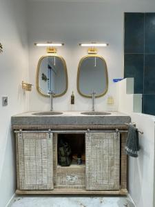 two sinks in a bathroom with two mirrors at La Kazbanon in La Possession