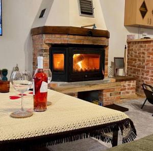 a bottle of wine and a glass on a table with a fireplace at VikendicaDM in Hrvačići