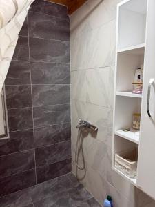 a bathroom with a shower with a black and white tile at VikendicaDM in Hrvačići