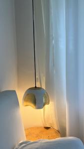 a lamp hanging over a bed next to a curtain at THHPSOCIETY - Exstacy stays & cafe - Your Romantic & Cozy Getaway - Mountain view , Hot tub , Parking - MUKTESHWAR in Mukteshwar