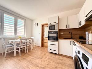 a kitchen with white cabinets and a table with chairs at Apartmánový byt Kostička 7 in Kadaň