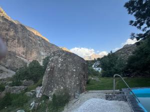 a large rock next to a swimming pool in a mountain at Sharsharai Haftkul in Panjakent