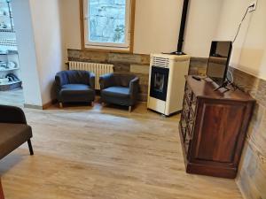 a living room with a tv and two chairs and a podium at Casa Lidia, ideal familias y grupos in O Grove +53 photos