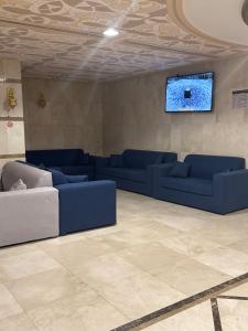 a living room with blue couches and a flat screen tv at فندق بلورة البشاير in An Naqāʼ
