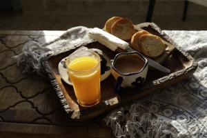 a tray with a glass of orange juice and bread at THHPSOCIETY - Exstacy stays & cafe - Your Romantic & Cozy Getaway - Mountain view , Hot tub , Parking - MUKTESHWAR in Mukteshwar