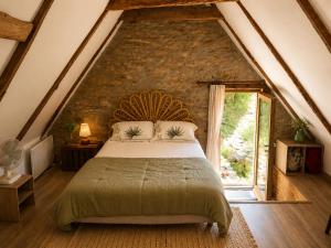 a bedroom with a large bed with a stone wall at Château de Taussac in Taussac