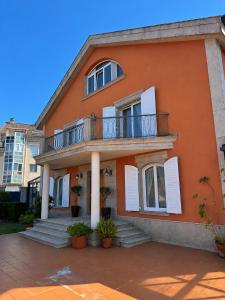 an orange house with a balcony and stairs at Xanela da Ría in Quenje