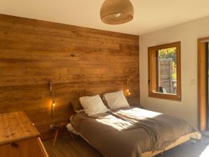 a bedroom with a bed with a wooden wall at Chalet Chante Guisane in Saint-Chaffrey