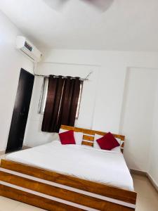 a bedroom with a white bed with red pillows at Hotel Deluxe in Hinjewadi +10 photos