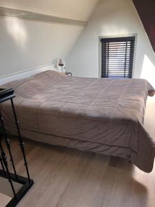 a large bed in a room with a window at Beachhouse Noteboom, omheinde tuin in Noordwijk aan Zee