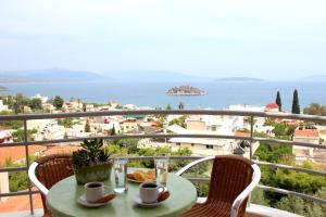 a table and chairs on a balcony with a view of the ocean at Amaryllis Hotel Apartments in Tolo