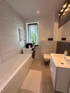a bathroom with a tub and a toilet and a sink at Apartament Modrzewia in Elblag