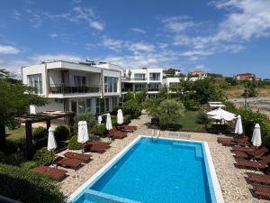 a resort with a swimming pool and chairs and a building at Ancient well in Sozopol