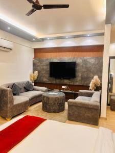 a living room with couches and a flat screen tv at The Origin Suites opposite Hyatt Dlf my pad Lucknow in Lucknow