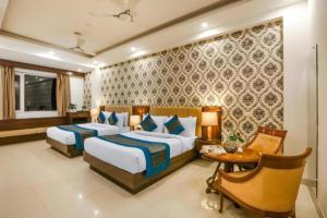 a hotel room with two beds and a table and a desk at Hotel Almati Inn Near IGI Delhi Airport - With Free Airport Pickup in New Delhi