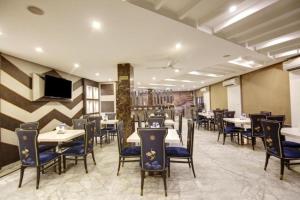 a restaurant with tables and chairs and a flat screen tv at Hotel Almati Inn Near IGI Delhi Airport - With Free Airport Pickup in New Delhi
