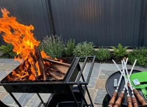 a fire pit with a bunch of hot dogs and tongs at AnArt resort in Vanadzor