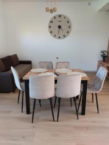 a dining room table with chairs and a clock on the wall at Nowy Zakątek in Paszkówka +6 photos