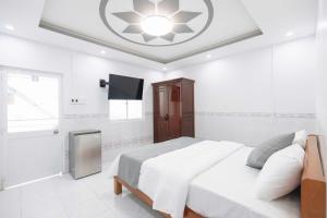 a white bedroom with a large bed and a tv at Hotel TRUNG LÀI in Tây Ninh