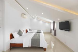 a white bedroom with a bed and a tv at Hotel TRUNG LÀI in Tây Ninh