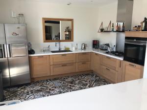a kitchen with wooden cabinets and a stainless steel refrigerator at Villa Maude & Jean in Lacanau-Océan