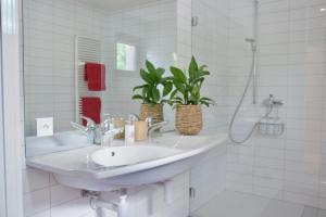 a white bathroom with a sink and a mirror at L'Effet Papillon - Maison d'hôtes in Sauges